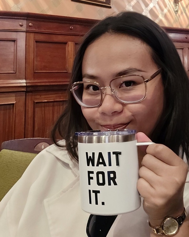 Oktifani Winarti smiling over a white mug printed “Wait for it.”